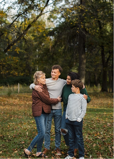 A family of four embracing outdoors in a park