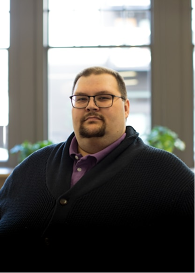 A working adult standing near a bright office window
